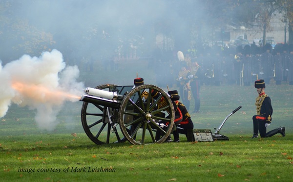 Men dressed in Napoleonic outfits firing a cannon on a battlefield